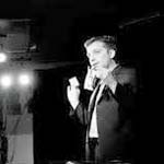 Magician David Corsaro black and white photo performing on a stage with lights above