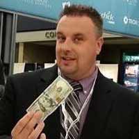 Magician Mike Seege is holding a $100 bill at a trade show about to perform